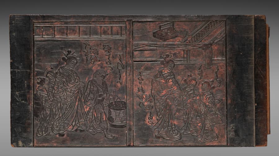 An Edo-period carved wooden printing block, figures cut in relief with dark ink still held in the grain
